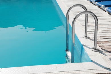 Modern swimming pool with ladder at resort