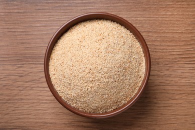 Photo of Fresh bread crumbs in bowl on wooden table, top view