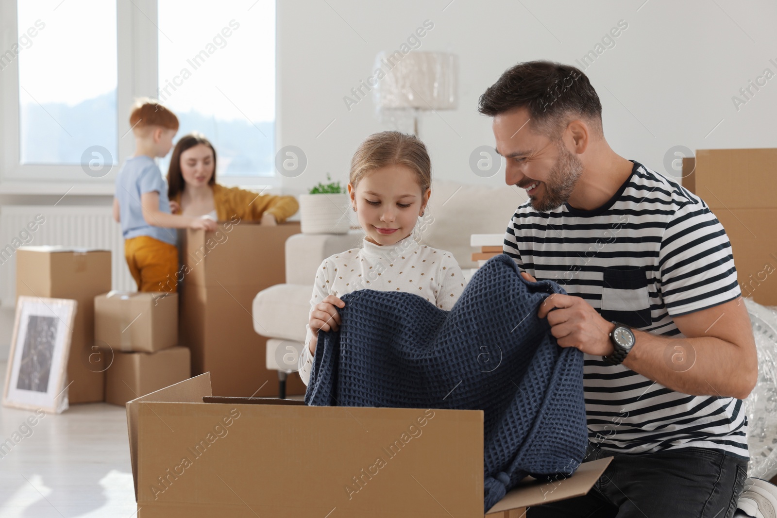Photo of Happy family unpacking boxes in new apartment. Moving day