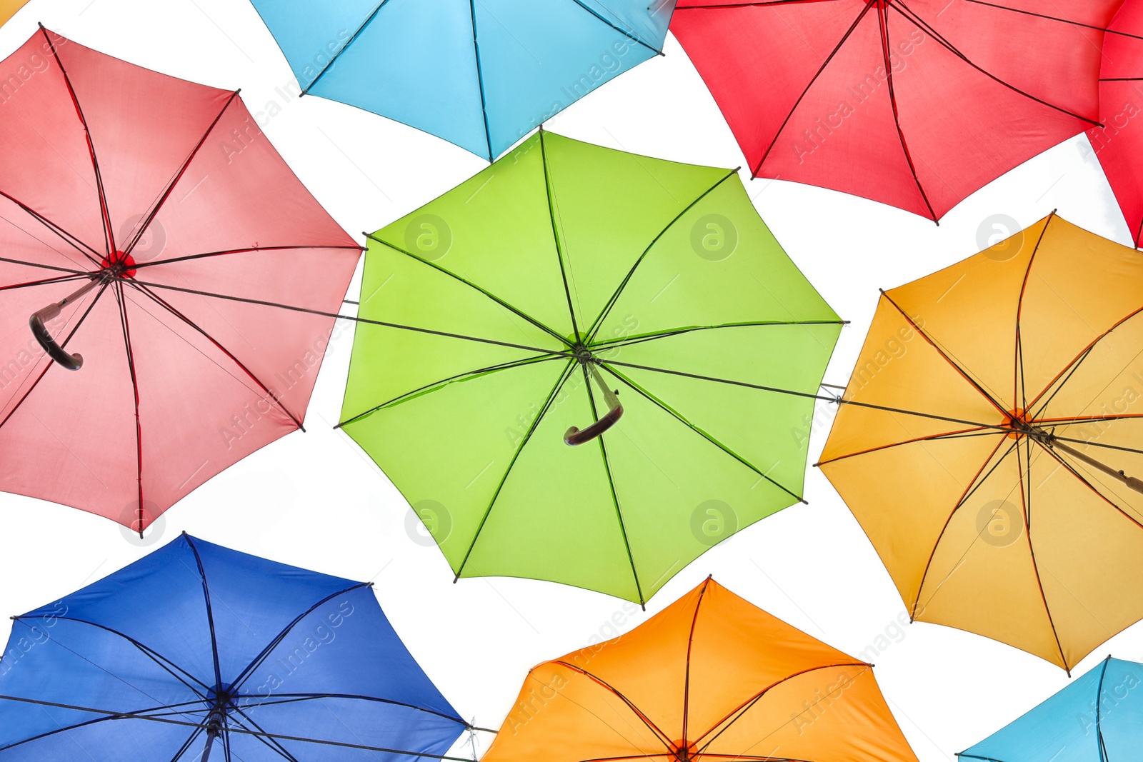 Photo of Many multicolored umbrellas on light background, bottom view