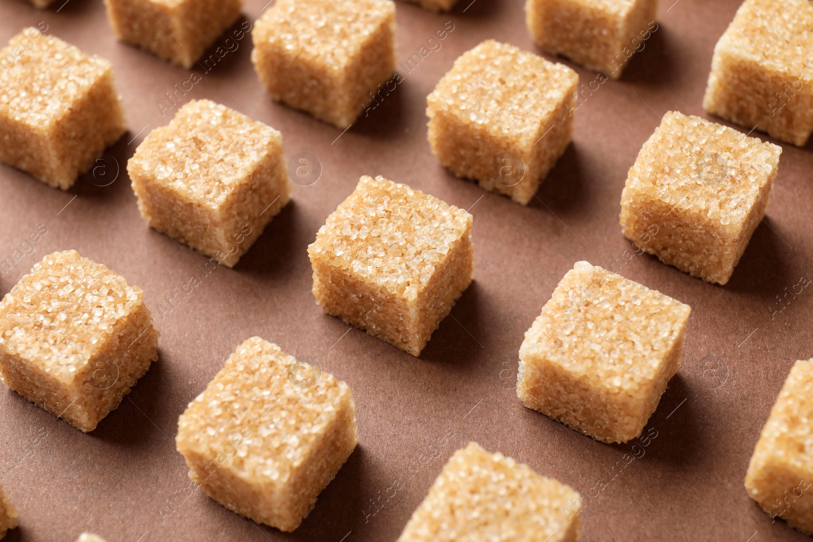 Photo of Brown sugar cubes on color background, closeup