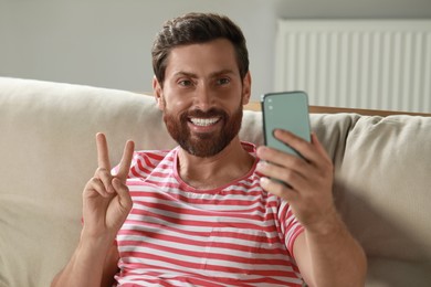 Photo of Handsome man taking selfie with smartphone at home