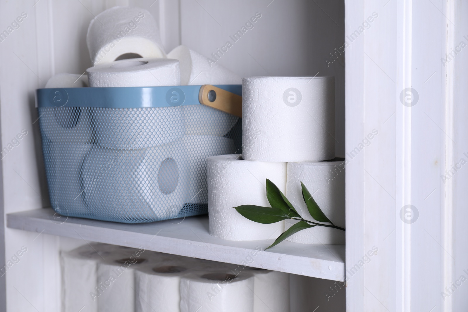 Photo of Toilet paper rolls and green leaves on white shelf