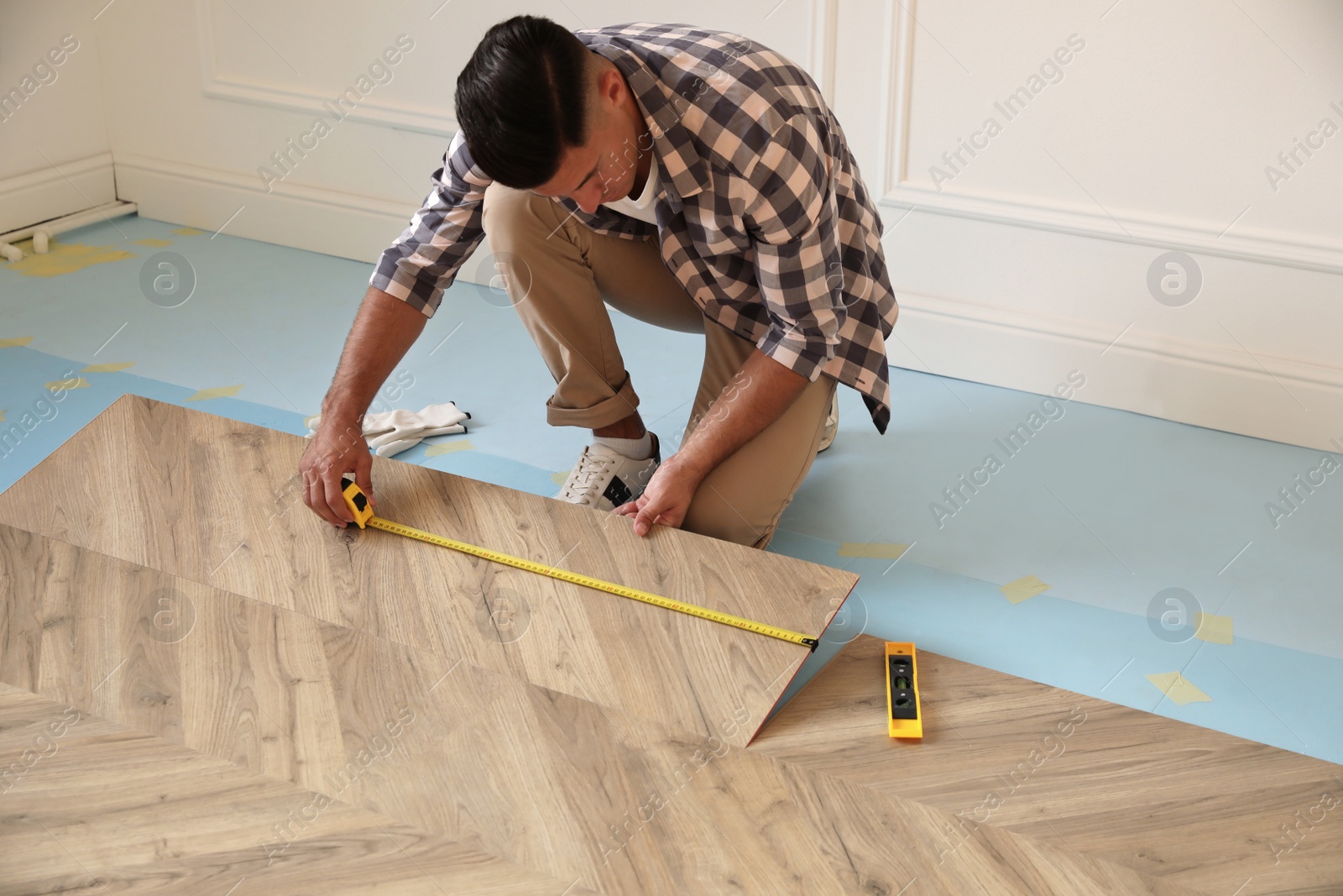 Photo of Professional worker installing new parquet flooring indoors