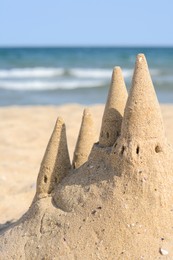 Photo of Beach with sand castle near sea on sunny day, closeup