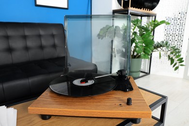 Photo of Vinyl record player on wooden table in living room