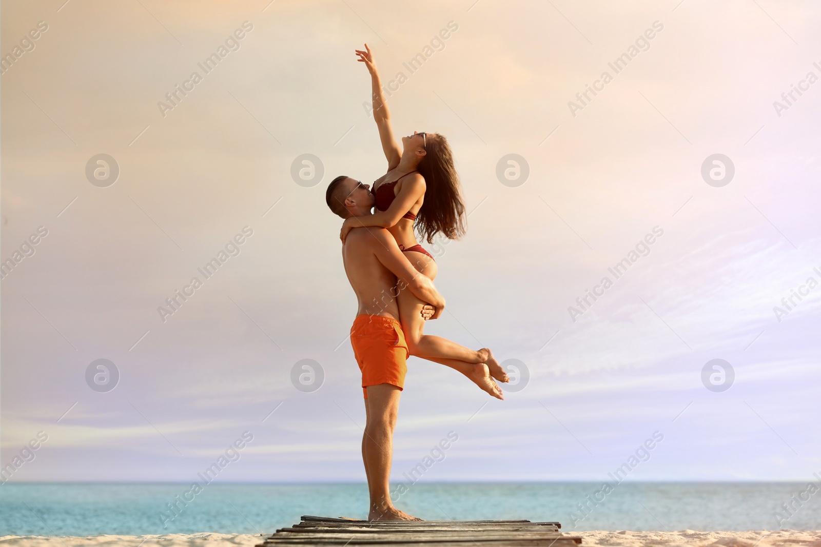 Photo of Young woman in bikini spending time with her boyfriend on beach. Lovely couple