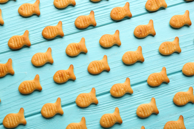 Photo of Delicious goldfish crackers on light blue wooden table, flat lay