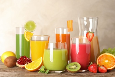 Photo of Glassware with different juices and fresh fruits on table