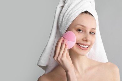 Photo of Washing face. Young woman with cleansing brush on grey background, space for text