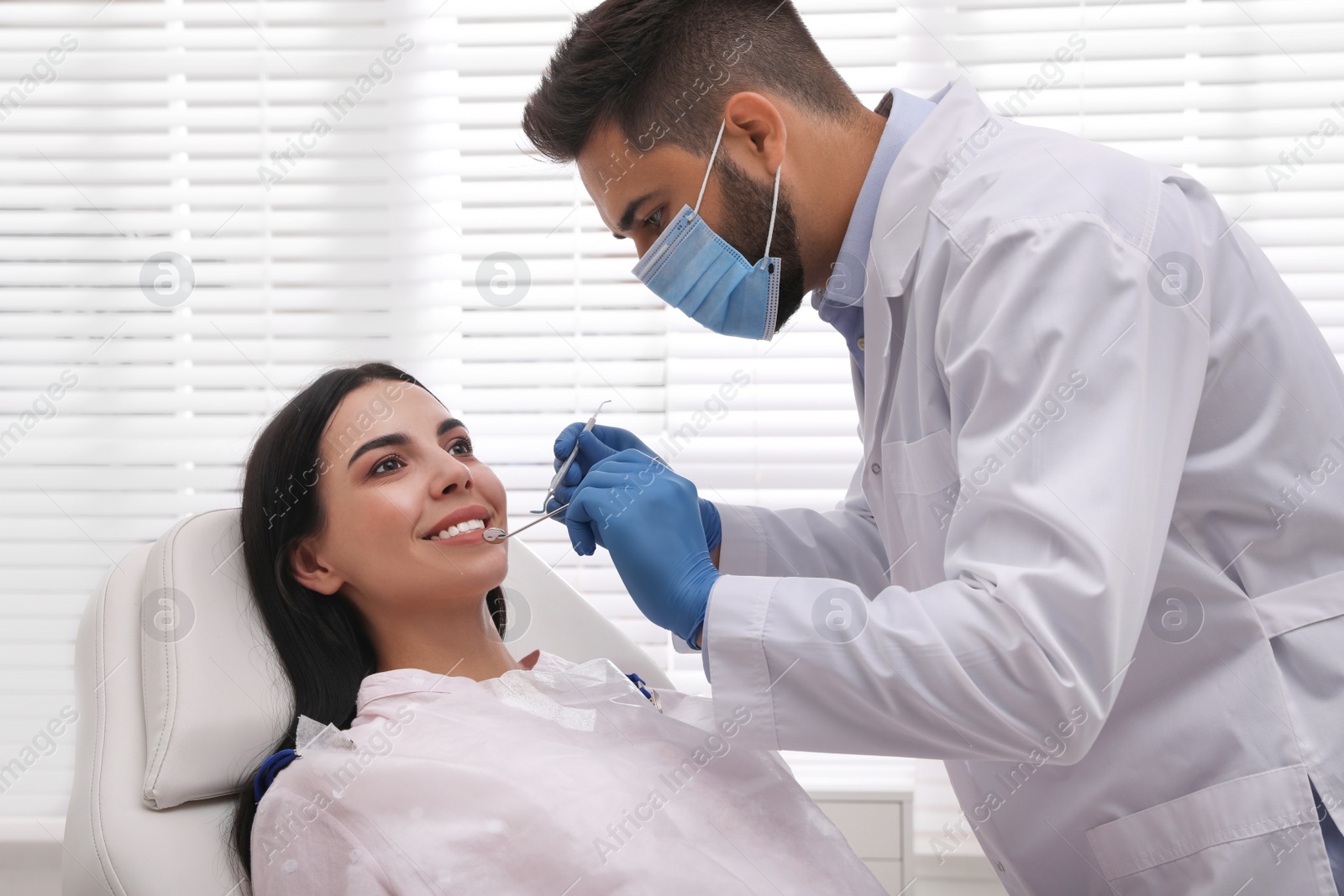 Photo of Dentist examining young woman's teeth in modern clinic
