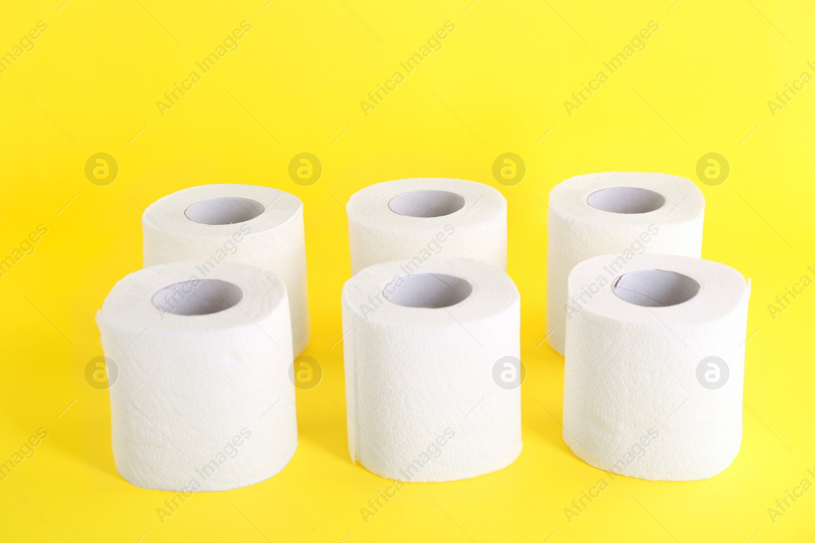 Photo of Many soft toilet paper rolls on yellow background