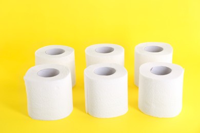 Photo of Many soft toilet paper rolls on yellow background