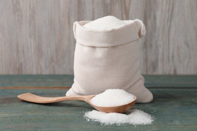 Photo of Sack bag and spoon with granulated sugar on light blue wooden table