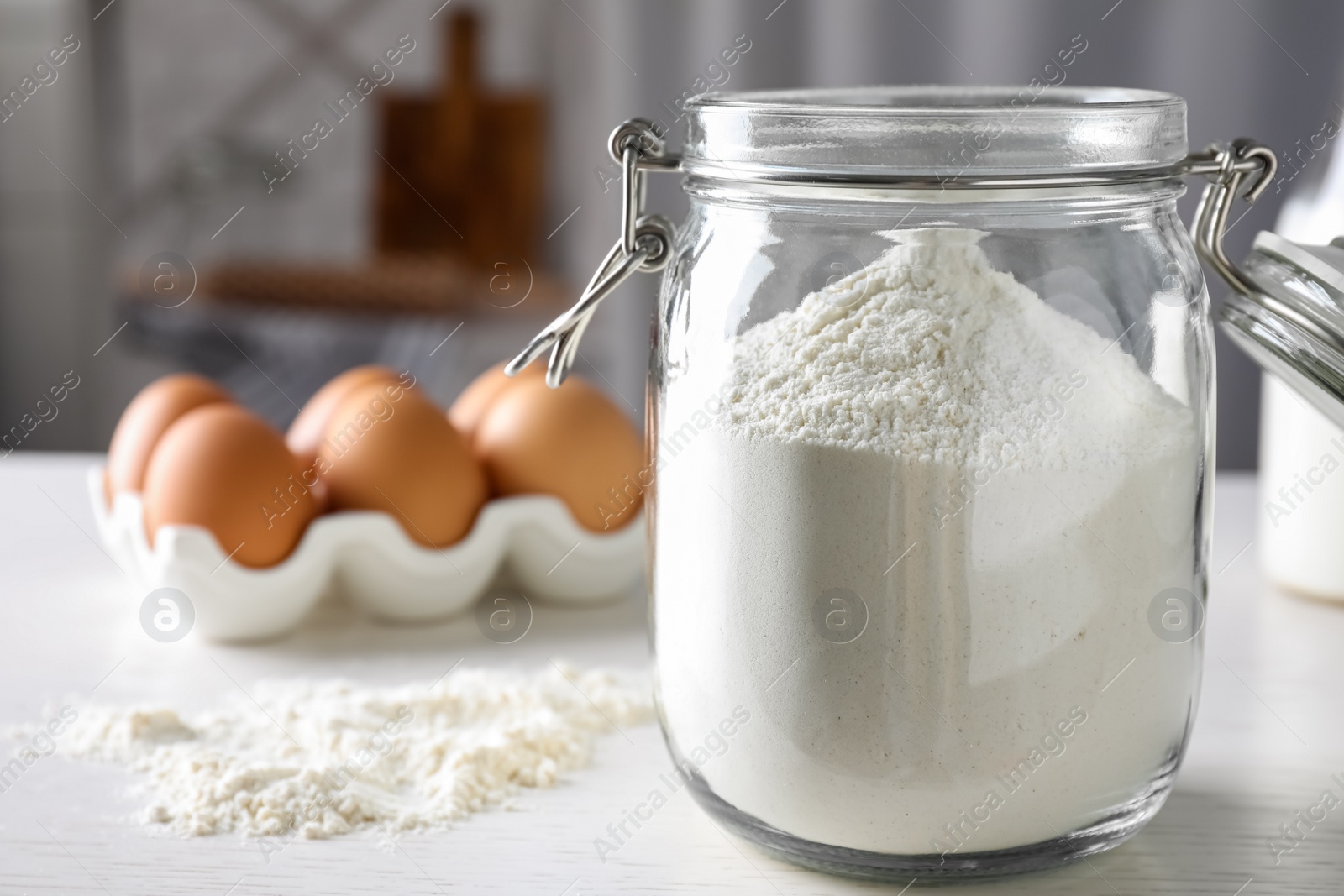 Photo of Glass jar with flour on white table indoors, closeup. Space for text