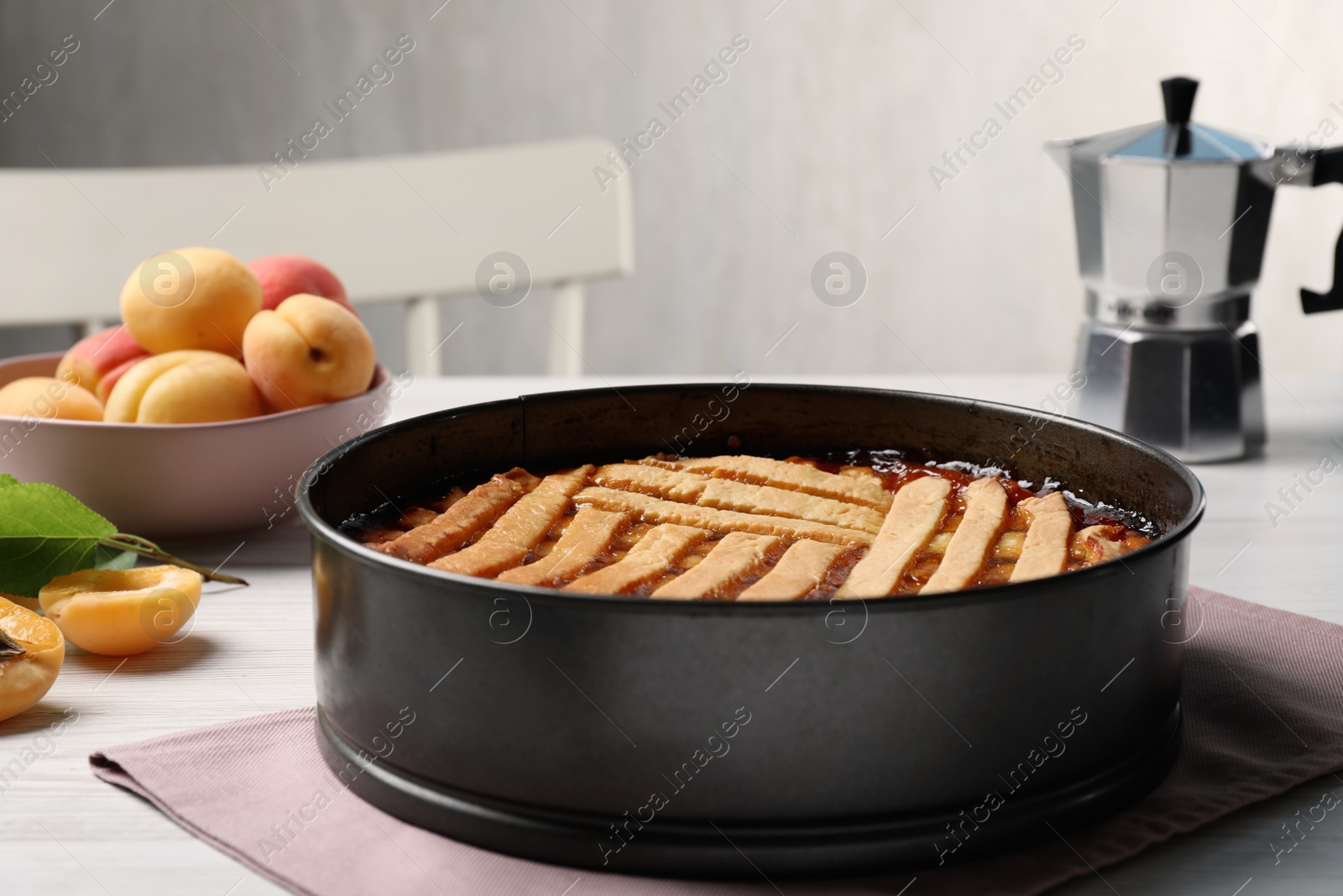 Photo of Delicious apricot pie in baking dish on white wooden table