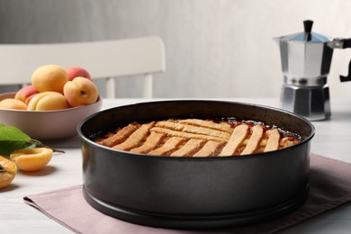 Delicious apricot pie in baking dish on white wooden table