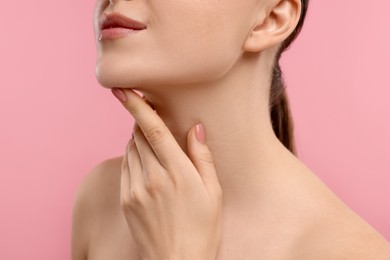 Photo of Woman touching her chin on pink background, closeup