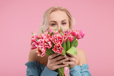 Happy young woman with beautiful bouquet on dusty pink background