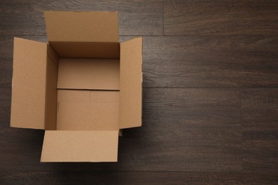 Photo of Empty open cardboard box on wooden table, top view. Space for text