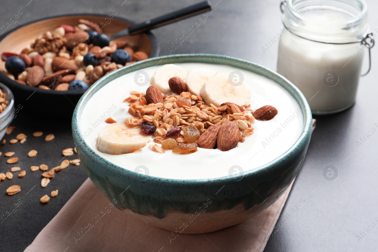 Photo of Bowl with yogurt, banana and granola on table