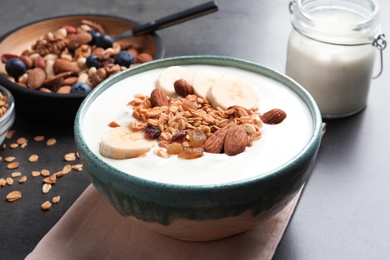 Photo of Bowl with yogurt, banana and granola on table