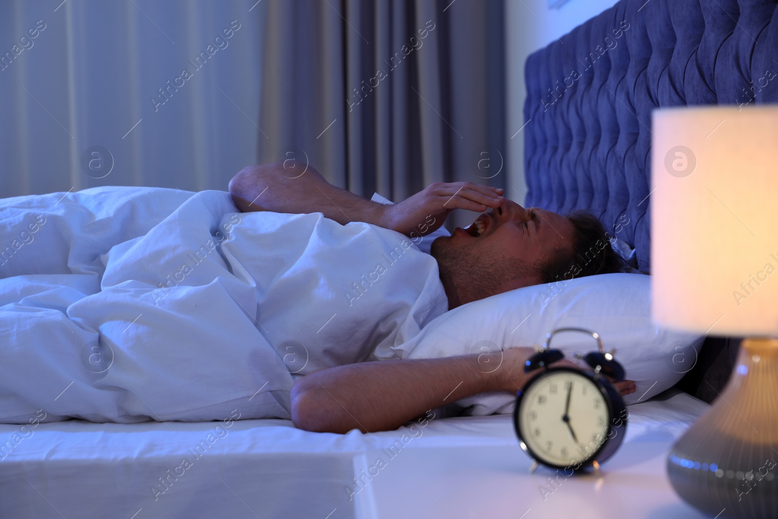 Photo of Sleepy young man lying on pillow at night. Bedtime