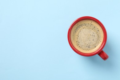 Photo of Tasty coffee in cup on light blue background, top view. Space for text