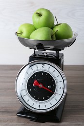 Photo of Kitchen scale with green apples on wooden table