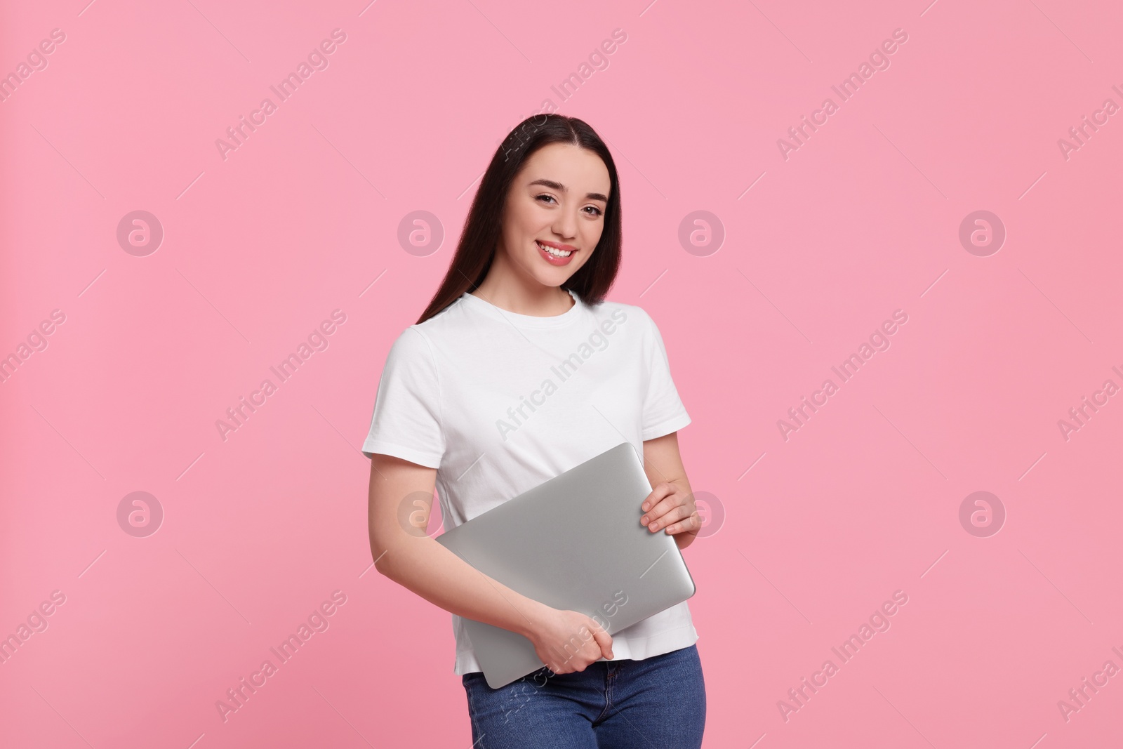 Photo of Smiling young woman with laptop on pink background