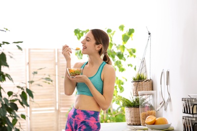 Young woman in fitness clothes having healthy breakfast at home