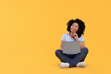 Photo of Happy young woman with laptop on yellow background. Space for text