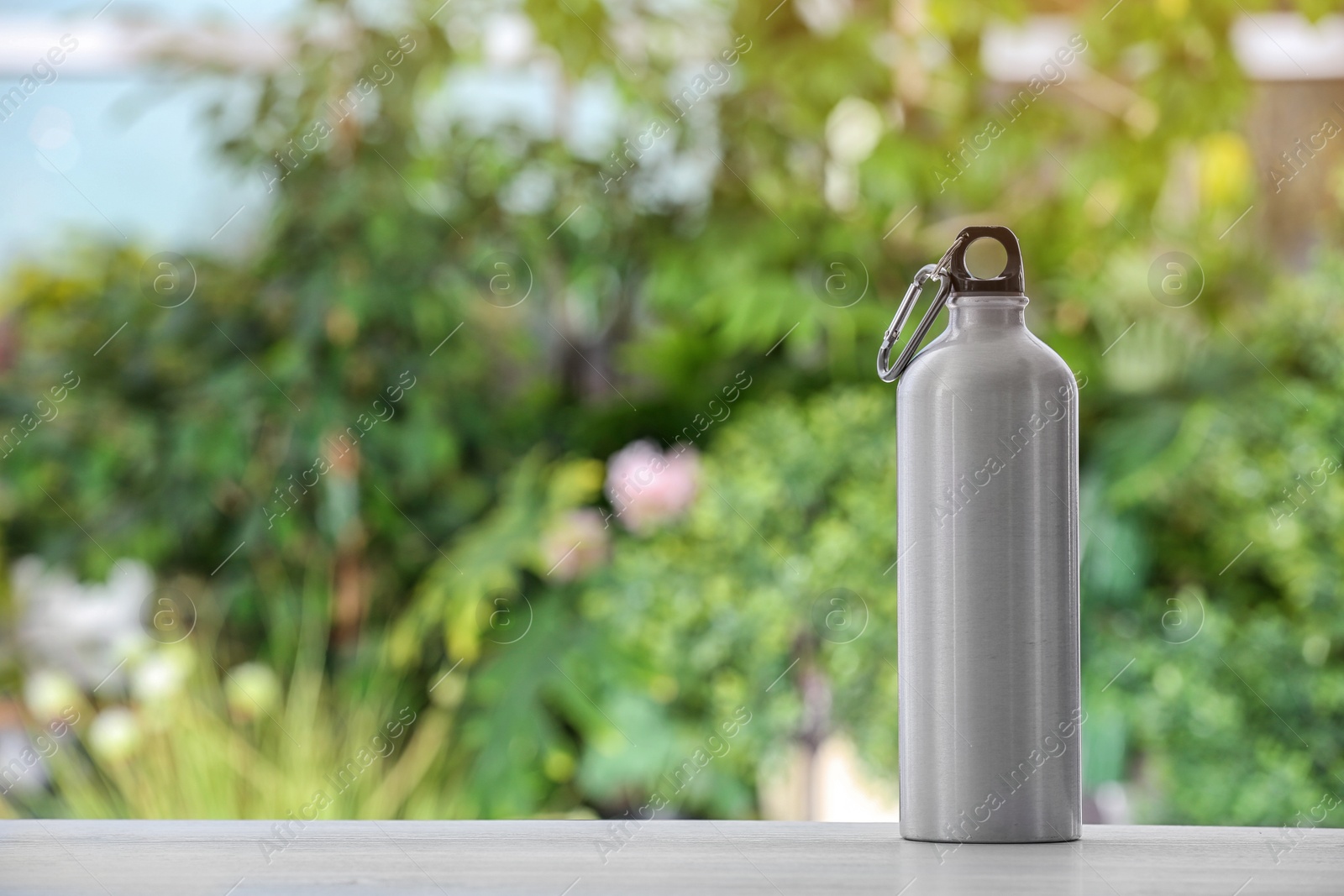 Photo of Sports water bottle on table against blurred background. Space for text