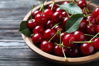Photo of Delicious ripe sweet cherries on dark wooden table, closeup