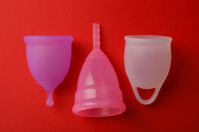 Photo of Different menstrual cups on red background, flat lay