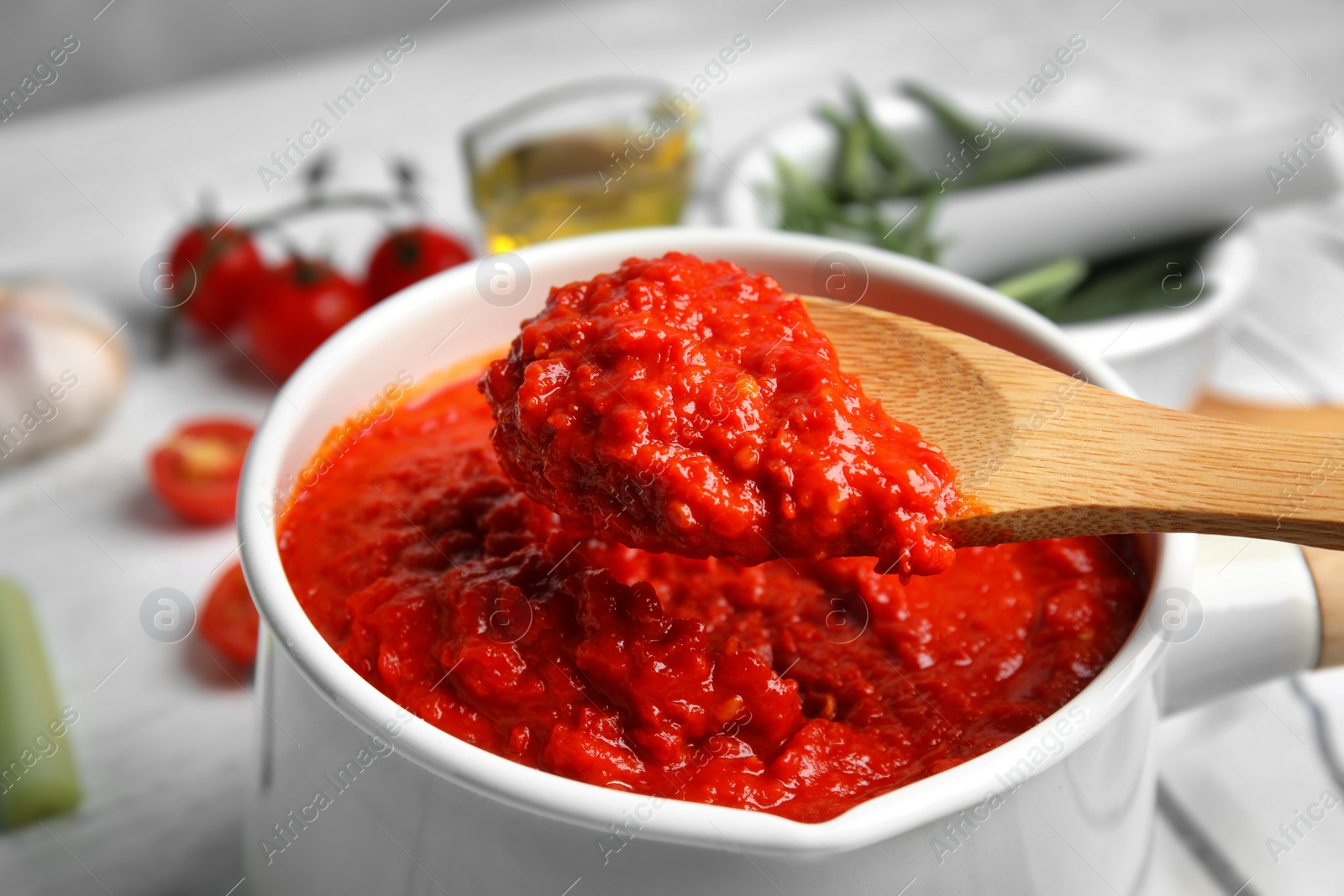 Photo of Spoon and pan with delicious tomato sauce, closeup view