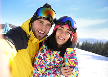 Photo of Young couple taking selfie at ski resort. Winter vacation