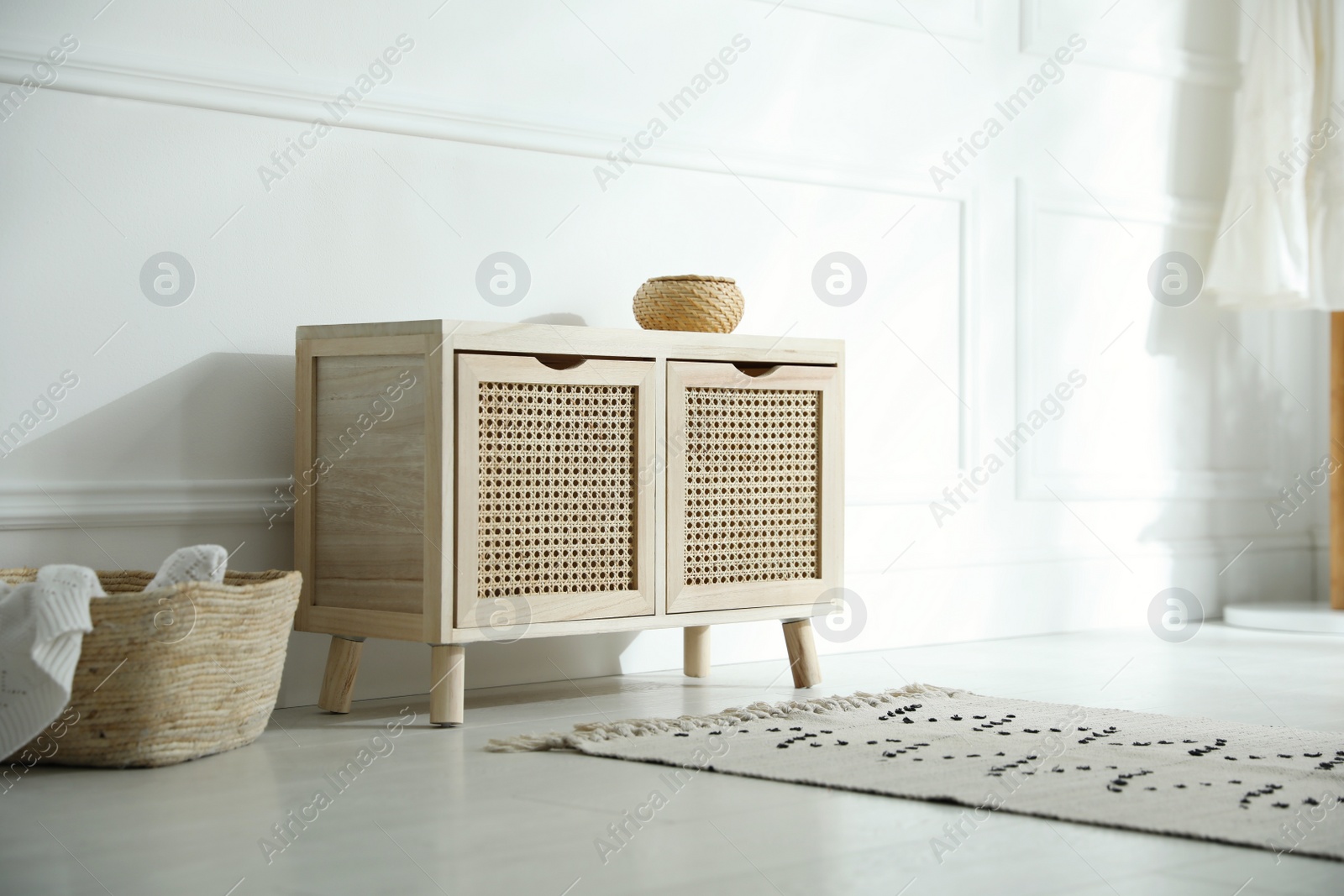 Photo of Wooden commode near white wall in room. Interior design