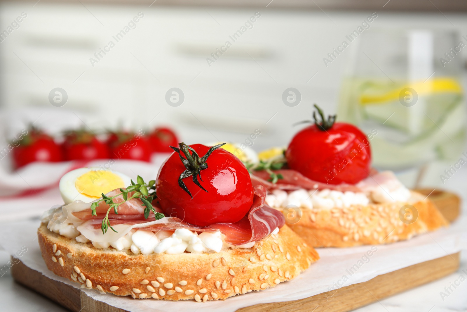 Photo of Cutting board of delicious bruschettas with prosciutto on white marble table