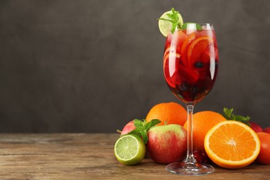 Photo of Glass of Red Sangria and fruits on wooden table, space for text