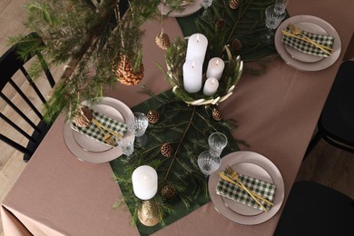Christmas table setting with burning candles and other festive decor, above view