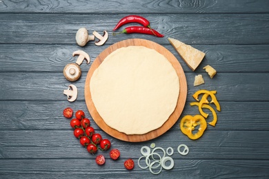 Photo of Dough and ingredients for pizza on wooden background, top view