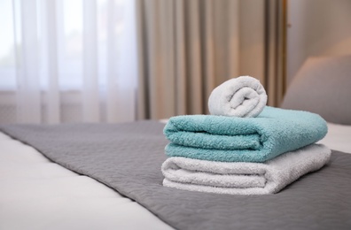 Soft clean towels on bed indoors. Space for text