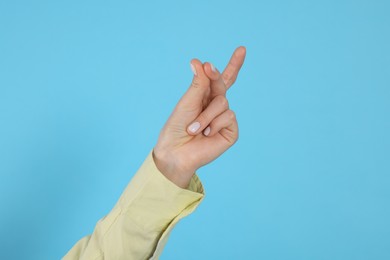 Photo of Woman snapping fingers on light blue background, closeup of hand