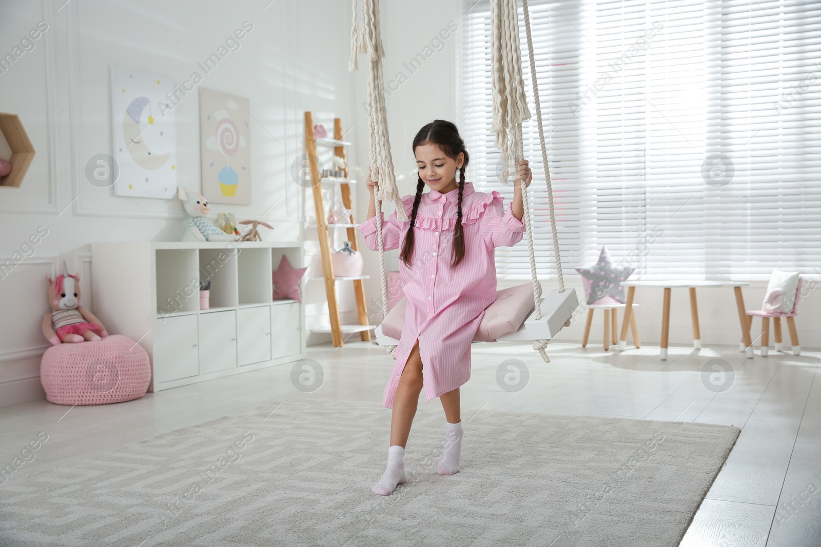 Photo of Cute little girl playing on swing at home