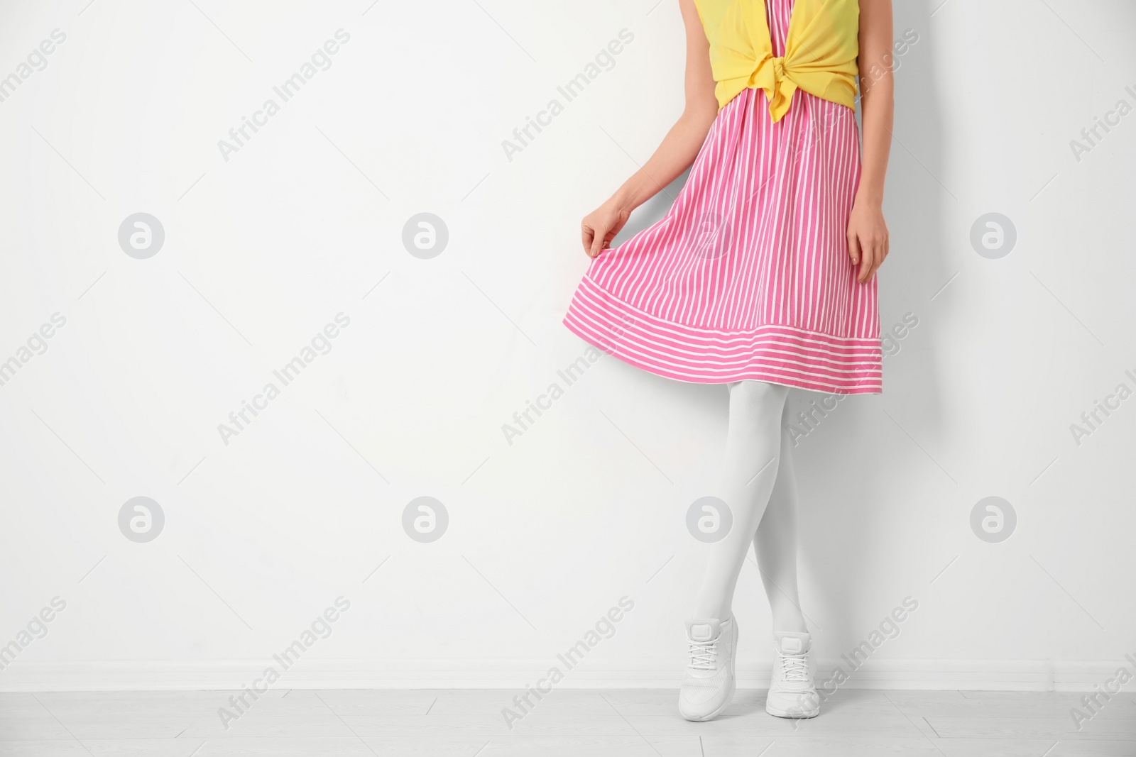 Photo of Woman wearing tights near white wall, closeup. Space for text