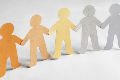 Paper people holding hands on light background. Unity concept