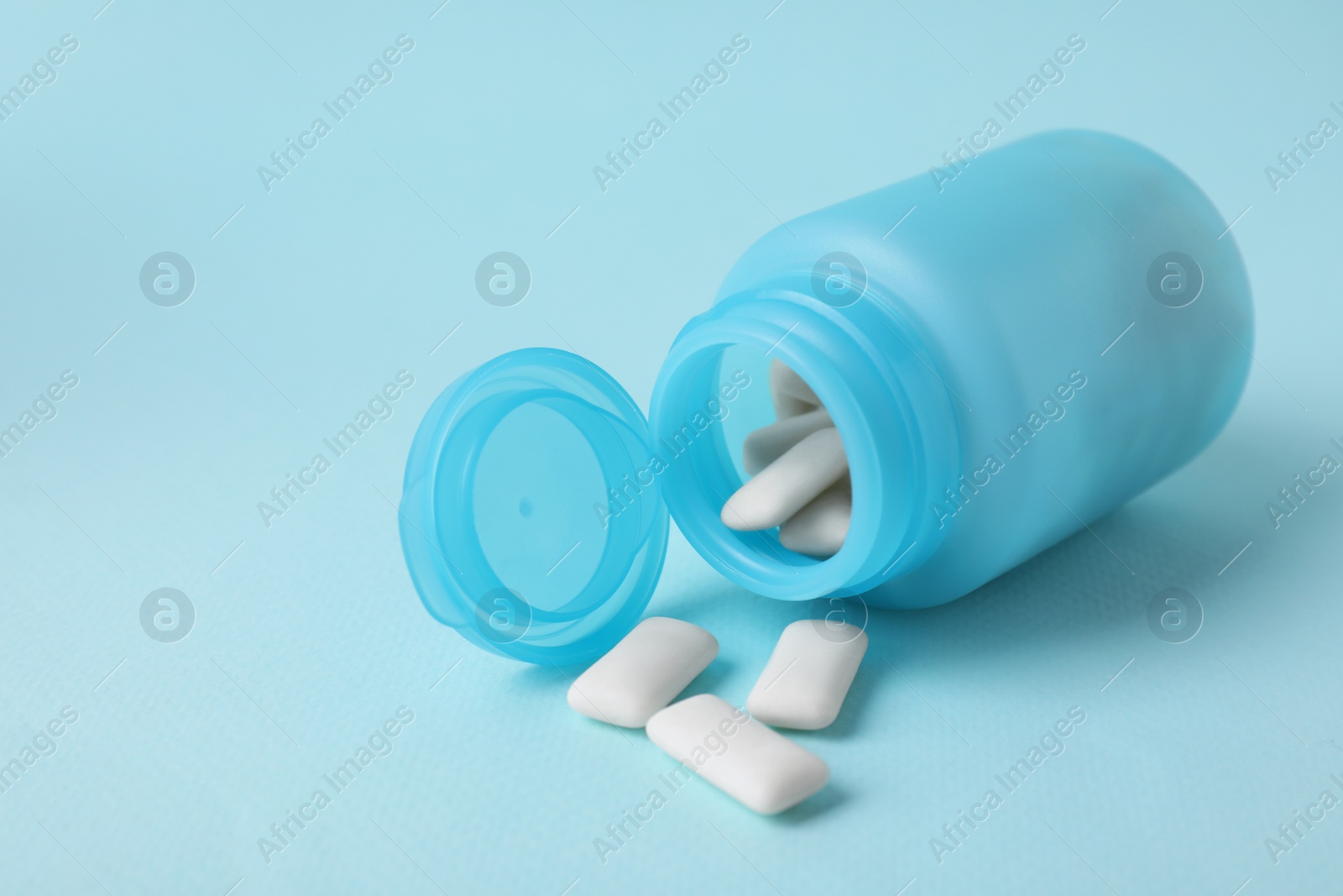 Photo of Color jar with chewing gums on light blue background, closeup. Space for text