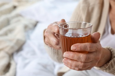 Elderly woman with cup of hot tea indoors, closeup. Home care service