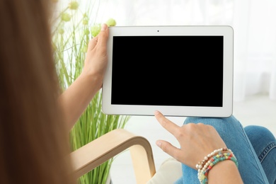 Woman holding tablet with blank screen indoors. Mockup for design